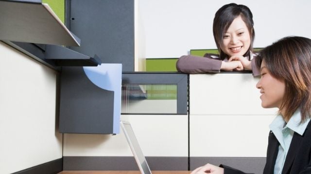 a woman talking to another woman in an office